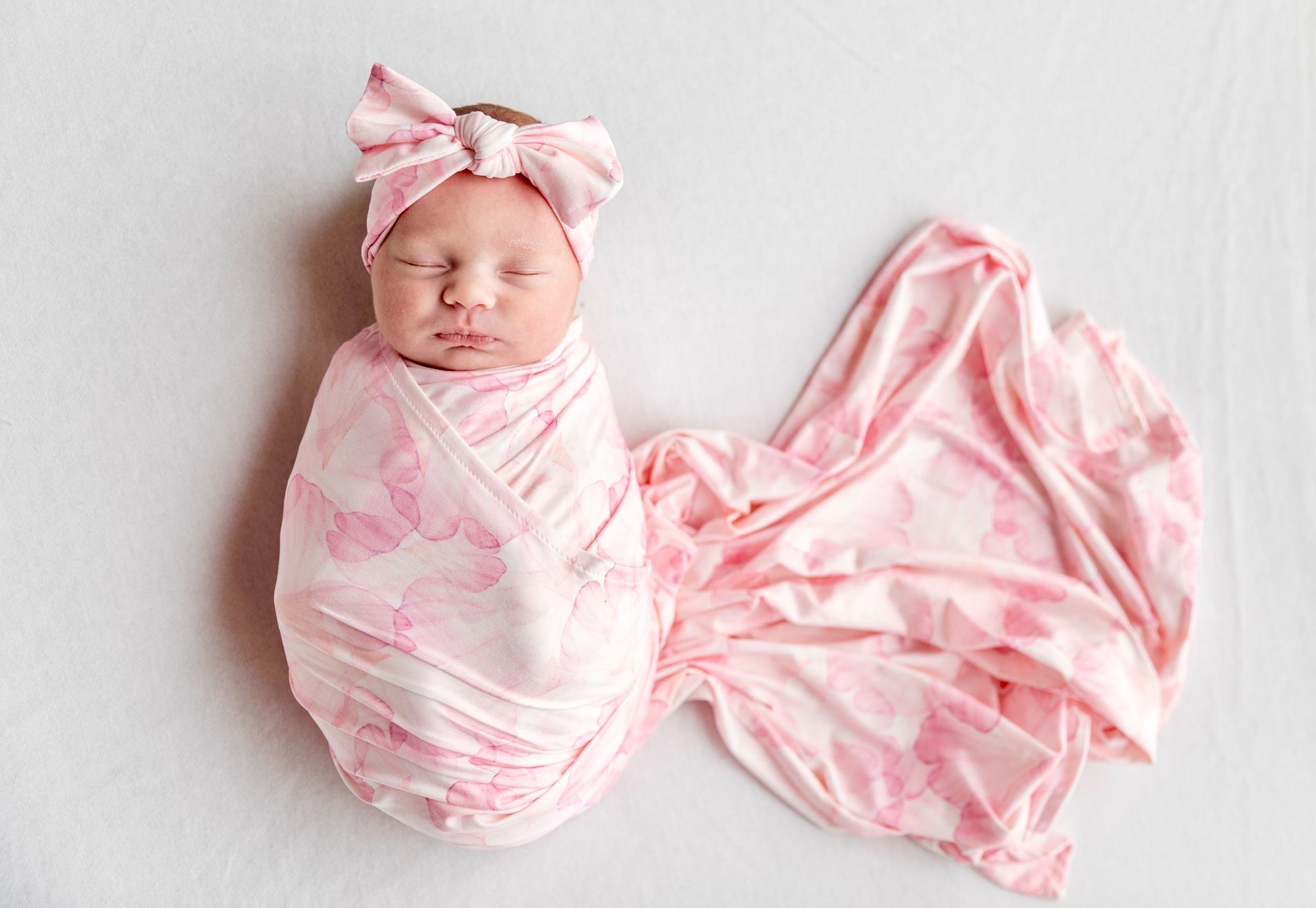 Baby in a pink floral swaddle with a matching bow