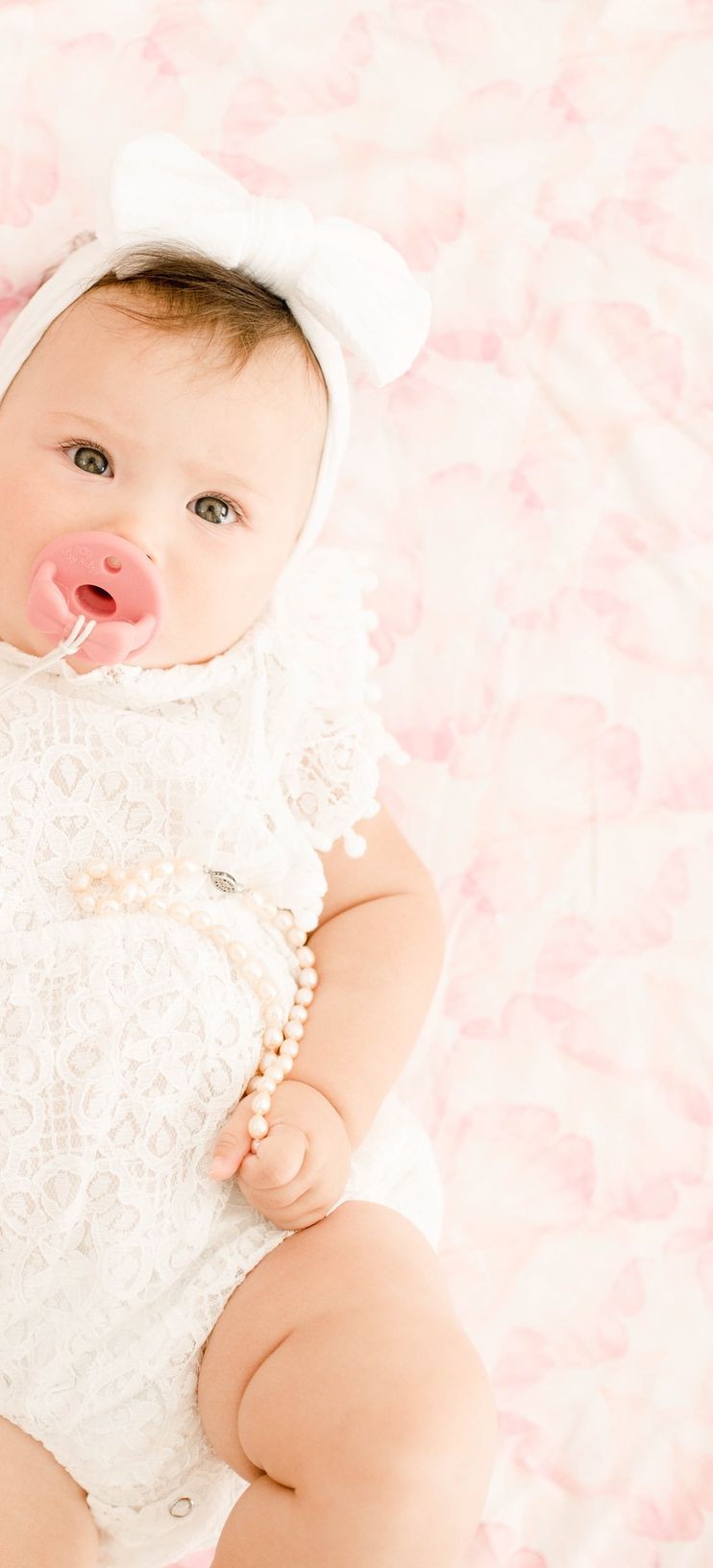 Baby with a pink floral swaddle and lace clothing